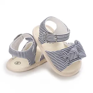 Primo piano di sandali per neonati a righe blu navy con grazioso fiocco e fibbia