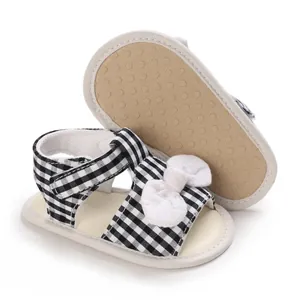 Detailansicht von Baby-Sandalen mit schwarz-weißem Gingham-Muster und Schleife