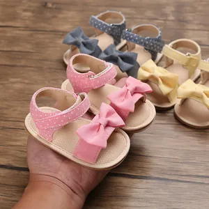 Close-up of pink baby sandals with bow and polka dots, soft sole for toddlers