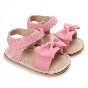 Detailed view of pink polka dot baby sandals featuring a soft sole and bow accent
