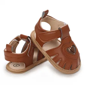 Détail de sandales marron pour bébé fille avec motif cœur ajouré et semelle souple.