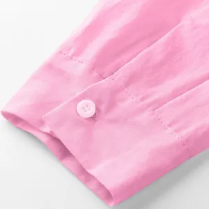 Close-up detail of pink men's solid shirt cuff with a white button and neat stitching