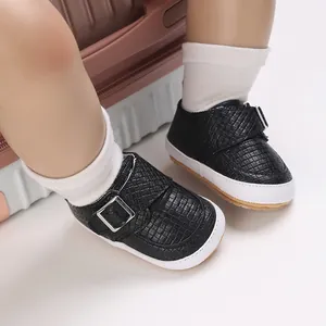 Detail von schwarzen geflochtenen Babyschuhen mit Silberschnalle und weicher Sohle