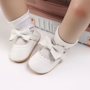 Detail view of white baby princess shoes with a large bow and soft sole.