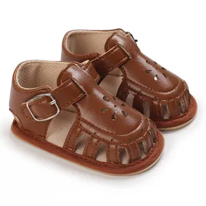 Makroansicht brauner Baby-Sandalen mit weicher Sohle, Blumenmustern und Schnallenverschluss.