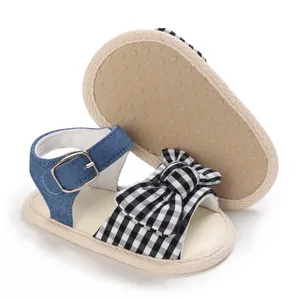 Primo piano dettagliato di sandali estivi per bambina con fiocco vichy e cinturino in denim