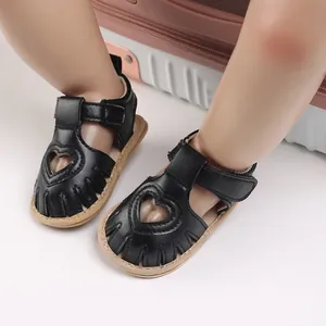 Détail de sandales bébé fille avec découpe en forme de cœur et cuir noir souple