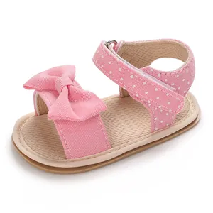 Detailed view of pink baby girl sandal featuring a cute bow and polka dot strap.