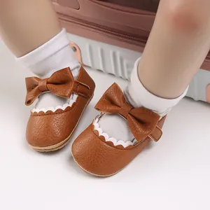 Close-up of brown baby walking shoes featuring large bows and decorative scalloped edges
