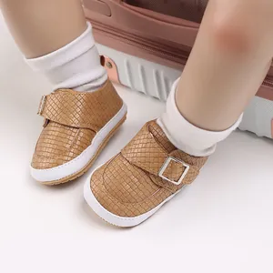 Nahaufnahme von hellbraun gewebten Babyschuhen mit Silberschnalle und Socken