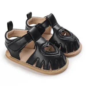 Gros plan de sandales noires pour bébé fille avec motif coeur ajouré et semelles souples