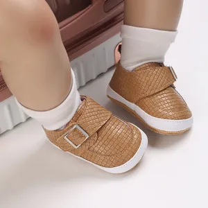 Nahaufnahme von hellbraun gewebten Babyschuhen mit weißen Sohlen und silbernen Schnallen