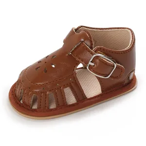 Detailaufnahme brauner Baby-Lauflernsandalen aus Kunstleder mit Schnalle und Lochmuster.