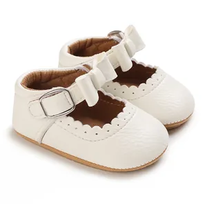 Close-up detail of white baby princess walking shoes with bow and scalloped trim