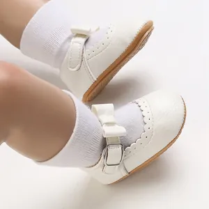 Close-up of white baby princess shoes with soft soles and delicate bow buckle