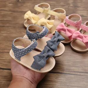 Detail of cute baby girl summer sandals with bows and polka dots on wood