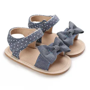 Detailed view of baby girl denim polka dot sandals featuring a large bow and soft sole design