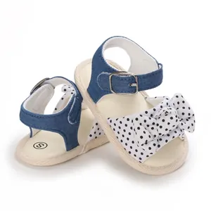 Dettaglio sandali estivi per neonata con cinturini in denim e fiocco a pois neri.