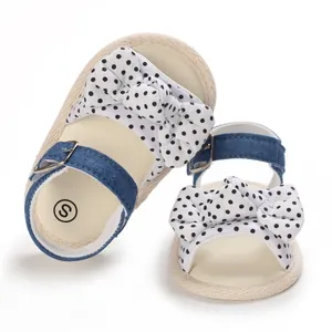 Dettaglio di sandali per neonata con fiocco a pois e cinturino in denim blu scuro