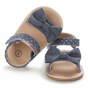 Macro detail of blue denim baby girl sandals with a decorative bow and polka dot straps