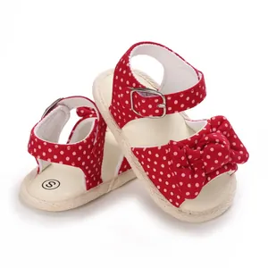 Dettaglio dei sandali rossi a pois per neonata con grande decorazione a fiocco