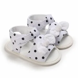 Classic white baby sandals with black polka dots and cute bow accent for infant girls