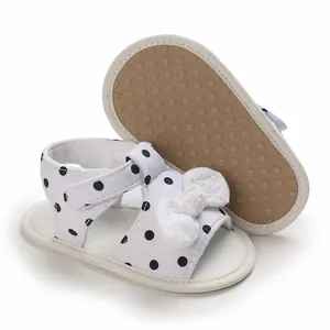 White infant sandals with black polka dots and decorative bow for first walking steps