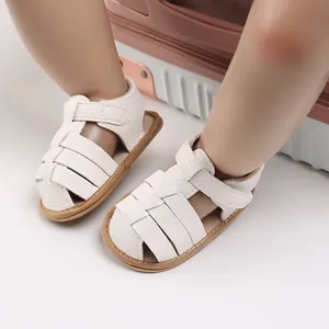 Close-up detail of white soft-sole baby sandals with woven straps for 0-1 year infants