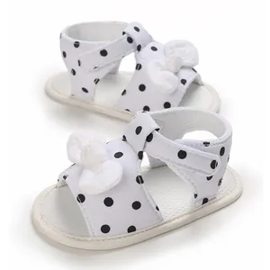 Detailed view of white baby girl cloth sandals featuring black polka dots and white bow