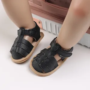 Close-up of black faux leather baby sandals with soft soles and velcro strap closure.