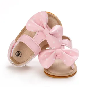 Detalle de sandalias rosas para bebé niña con lazos de lunares blancos