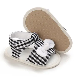 Detail view showing baby gingham sandals with white bow and non-slip sole texture