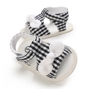 Detailed view of baby girl cloth sandals with black and white gingham and white bows