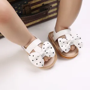 Sandalias blancas para bebé niña con lazo de lunares negros y suela blanda