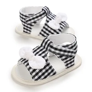 Detailed shot of black and white checkered baby pre-walker sandals with white crochet bows