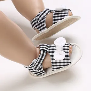 Detail view of black and white gingham baby sandals with white bow decoration