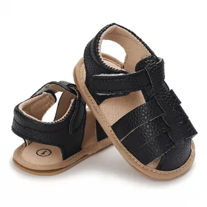 Close-up of black textured faux leather baby sandals with soft soles and velcro straps