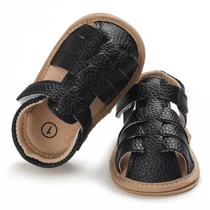 Macro detail showing black textured faux leather baby sandals with soft tan non-slip soles