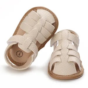 Detail of beige baby sandals with soft soles and woven textured faux leather straps.