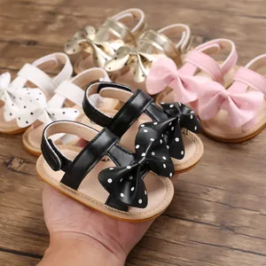 Detalle de sandalias para bebé niña con lazo de lunares y suelas blandas antideslizantes