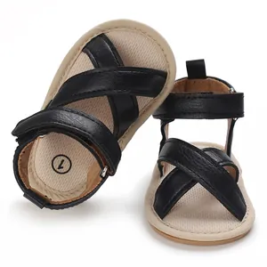 Vue détaillée de sandales de marche pour bébé avec brides croisées noires et semelles souples.