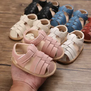 Detail view of pink baby sandals with woven leather texture and adjustable velcro strap.