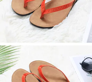 Close-up of stylish orange thong sandals with laser-cut patterns on a soft white shag rug.