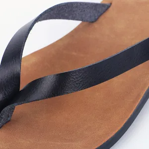Close-up of minimalist black straps and brown textured footbed of women's flip-flops.
