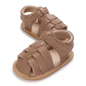 Macro view of brown faux leather infant walking sandals with soft sole and straps