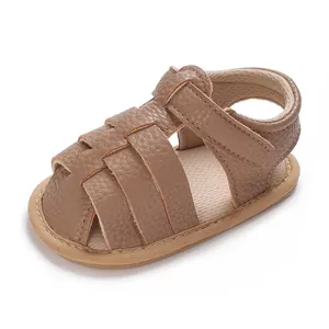 Macro view of brown faux leather baby sandal with Velcro strap and closed toe design