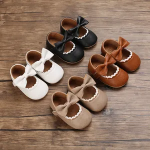 Collection of soft-sole baby princess shoes with bows in four colors on wood.