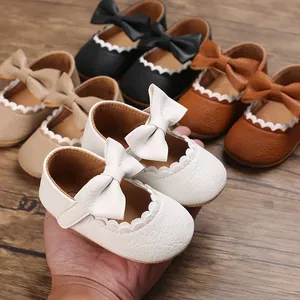 Close-up of white baby girl walker shoes with a cute bow and scalloped trim decoration