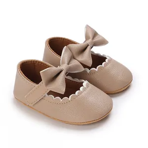 Macro view of beige baby princess shoes featuring decorative bows and scalloped edges