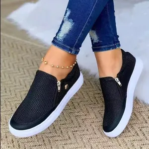 Λεπτομέρεια μαύρα γυναικεία sneakers με πλέγμα, λευκή επίπεδη σόλα και φερμουάρ στο πλάι